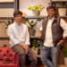 Two startup founders posing in a modern office space with indoor plants and wooden shelving in the background.