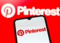 Pinterest logo displayed on a smartphone screen with the Pinterest brand logo in the background, representing the platform’s role in digital search and discovery.